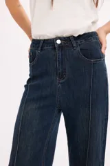 Jean de tiro alto en color azul oscuro, con costuras verticales decorativas en el frente y cierre de botón metálico.