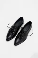 Zapato acordonado de cuero color bordó, con punta fina y diseño estilo oxford. Presenta cordones al tono y detalles de ojales metálicos dorados.