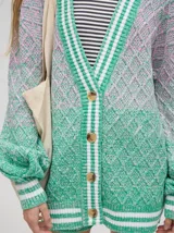 Cardigan oversize de algodón con diseño tejido a rombos en tonos degradados de marrón y blanco. Presenta cuello en V, cierre frontal con botones de madera y puños y dobladillo con rayas blancas.