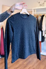 Conjunto de dos piezas compuesto por una remera de manga larga y un pantalón tipo palazo, confeccionado en tejido elastizado con acabado brillante y textura lineal. La remera presenta cuello redondo y ajuste al cuerpo, mientras que el pantalón posee un corte recto y holgado.