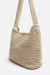 Bolso de hombro color crudo, tejido en macramé de algodón. Tiene un compartimento principal con cierre de imán y un bolsillo plano interior.