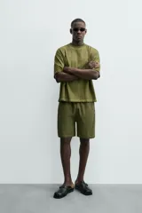 Bermuda de algodón color verde oliva, con corte relajado y textura acanalada vertical. Presenta cintura elástica con cordón interior y bolsillos laterales y trasero.