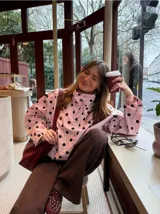 Chaqueta ligera de color amarillo con estampado de lunares negros, cuello alto, mangas largas anchas y cordón ajustable en el dobladillo inferior.
