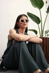 Pantalón de corte amplio y tiro alto, confeccionado en tela con textura tipo lino. Presenta un diseño envolvente en la cintura con un lazo lateral para anudar, creando un efecto de superposición frontal.