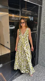 Vestido largo estampado con escote en V profundo y tirantes anchos. El diseño presenta un frunce o nudo en el centro del busto y tajos laterales en la falda.