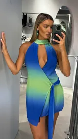 Vestido corto con diseño degradado en tonos azul y verde, de cuello halter con abertura frontal y detalle de nudo lateral con lazo.