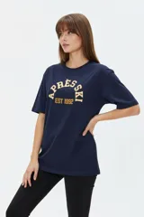 Remera de algodón negra con cuello redondo y mangas cortas, de corte holgado. Presenta estampado frontal en tonos de verde con la inscripción 'New York City Brooklyn' y el logo 'NY' rodeado de laureles.