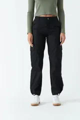 Pantalón cargo color beige de tiro medio, con bolsillos laterales tipo cargo y puños ajustables en los tobillos.