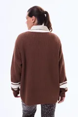 Sweater de punto color marrón con cuello redondo, puños y cuello con detalles de rayas blancas en contraste. De corte holgado y manga larga.