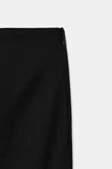 Pantalón capri negro de tiro medio con aberturas laterales en el bajo y cierre lateral con cremallera oculta.