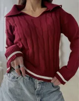 Sweater de punto con diseño de trenzas, cuello en V con solapa tipo polo, manga larga y puños con detalle de franja negra en contraste.