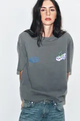 Camiseta de algodón con efecto lavado, corte oversize, cuello redondo y manga corta. Presenta estampados gráficos en el frente.