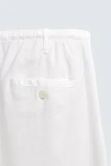 Pantalón de corte regular fit confeccionado en mezcla de algodón y lino. Presenta cintura elástica con cordón ajustable, cierre frontal con cremallera y botón, bolsillos laterales y bolsillo trasero de vivo con botón.