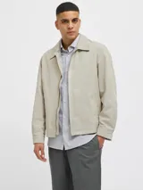 Campera aviadora color beige, de corte clásico, con cuello camisero, cierre frontal con cremallera, bolsillos laterales y puños elastizados.