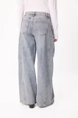 Jean de corte barrel con diseño de pierna ancha y tiro medio, confeccionado en denim de lavado claro. Presenta costuras laterales marcadas y un pequeño bordado del logo en el bolsillo delantero.