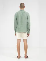 Camisa de manga larga confeccionada 100% en lino, color verde claro, con calce recto y relajado. Presenta frente abotonado con botones de coco con logo y el patch característico de Polonio.