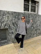 Conjunto compuesto por remera de manga larga oversize a rayas horizontales blancas y negras con escote bote, y pantalón negro de corte flared.