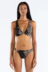 Bombacha de bikini con estampado animal print tipo cebra en tonos negro y beige, confeccionada en jacquard. Cuenta con un aro metálico decorativo en el lateral de la cadera.