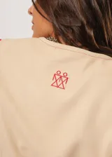 Chaleco beige con escote en V, sin mangas y cierre frontal con botones. Presenta pespuntes en color rojo y logo bordado en la espalda.