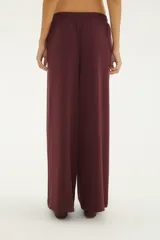 Pantalón ancho bordó de talle alto con cintura elástica fruncida y cordón ajustable del mismo tejido, bolsillos laterales y caída fluida.