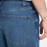 Pantalón tipo carpintero de corte holgado, confeccionado en denim azul con costuras reforzadas, bolsillos traseros amplios y bolsillo lateral utilitario.