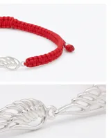 Pulsera de hilo rojo tejida en macramé con dije central en forma de ala de plata 925 y terminaciones con esferas de plata. Diseño regulable.