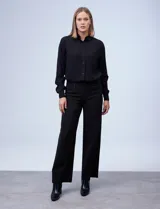 Pantalón de vestir de corte wide leg color negro, con cintura alta, detalle de botones decorativos en la parte frontal y bolsillos laterales.