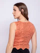 Top corto color salmón con estampado abstracto en marrón, sin mangas, con cuello redondo y terminación ondulada en el ruedo.