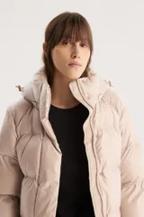 Campera puffer corta color beige con capucha desmontable, cierre frontal con cremallera y botones a presión, y cordón ajustable en el ruedo. Diseño acolchado con bolsillos laterales.