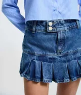 Short pollera de jean azul con diseño de cintura cruzada, doble abotonado y pliegues amplios en el ruedo. Confeccionado en algodón, combina la comodidad de un short con la estética de una minifalda.