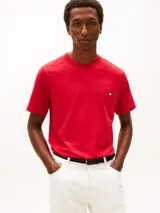 Remera de cuello redondo y manga corta, confeccionada en algodón regenerativo. Presenta un diseño liso en color rojo con un pequeño logo bordado en forma de escudo y la bandera distintiva de la marca en el pecho.