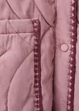 Chaqueta oversize acolchada de color rosado con diseño pespuntado en zigzag, cuello camisero, manga larga, bolsillos delanteros de parche y ribetes en contraste.