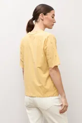 Remera blanca de manga corta con tejido de broderie, cuello redondo y diseño holgado.