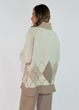 Sweater de cuello alto en color marrón chocolate, con diseño de rombos en la parte inferior en tonos naranja y bordó. Presenta mangas largas con puños acanalados y un corte holgado.