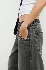 Jeans de tiro medio con cinco bolsillos, cintura doble a contraste y detalles de rotos. Cierre frontal con cremallera y botones metálicos.
