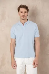 Remera tipo polo de piqué color celeste melange, con cuello y tapeta de dos botones en el mismo tono. Presenta un pequeño logo bordado en el pecho.