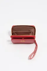 Billetera compacta de estructura rígida en piel vacuna color negro, con cierre de cremallera perimetral y tirador de tejido en color turquesa. Presenta el logo de la marca estampado en dorado en el frente.