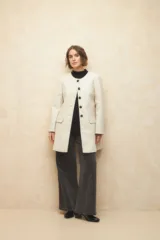 Tapado largo color crema, de paño, con cuello a la base y botones redondos veteados.