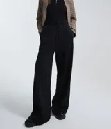 Pantalón de corte wide leg confeccionado en algodón con felpa, color marrón topo. Presenta cintura elástica con cordón ajustable y costuras verticales decorativas en el frente.