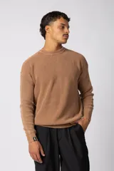 Sweater de punto grueso con textura waffle, de calce relajado y cuello redondo. Presenta puños y ruedo acanalados, con un pequeño parche con logo en el puño izquierdo.