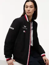Campera estilo bomber de Tommy Hilfiger en colaboración con Cadillac Formula 1® Team, color negro. Cuenta con cuello tipo béisbol, cierre frontal de cremallera y ribetes tejidos a rayas rojas, blancas y azules en el cuello, puños y dobladillo. Presenta parches bordados del equipo en el pecho.