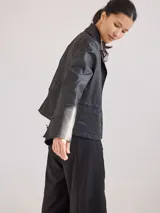 Chaqueta de jean azul oscuro, de corte corto y entallado, con cuello y solapa, y botones de madera en el frente.