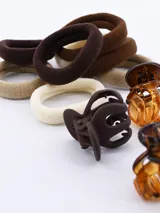 Pack de accesorios para el pelo que incluye cuatro mini pinzas de pelo en color marrón y ocho coleros en tonos marrón y beige.