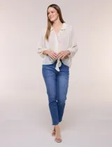 Blusa confeccionada en gasa semitransparente con sutil acabado plisado y estampado floral en tonos suaves. Presenta cuello solapa redondeado, escote en V y botonadura frontal. Mangas largas con puños elásticos y ruedo anudado en la parte inferior frontal.
