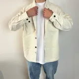 Sobrecamisa de pana en color tostado, con cierre frontal de botones, cuello clásico y dos bolsillos frontales con solapa y botón.
