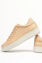 Zapatillas color beige claro, con capellada de cuero suave y acolchado, forro y plantilla de cuero vacuno, y suela de EVA. Tienen una plataforma de 3.8 cm en la parte trasera y 3.2 cm en la delantera.