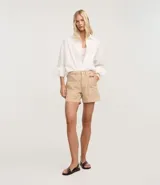 Short mom de tiro alto confeccionado en sarga de algodón, con diseño de bolsillos tipo carpintero en la parte frontal, cierre de botón y cremallera, y trabillas en la cintura.