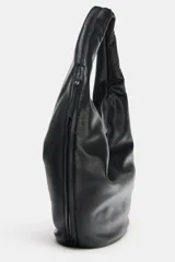 Bolso de hombro tipo saca en formato maxi, confeccionado en material sintético con acabado liso. Cuenta con asa única para llevar al hombro, cierre imantado en el compartimento principal, bolsillo lateral con cremallera y bolsillo interior con cierre.