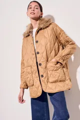 Campera color camel con diseño acolchado, cierre con botones a presión, cuello de piel sintética desmontable, bolsillos delanteros y puños ajustables con lazo.