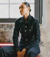 Campera de jean color azul oscuro, con diseño entallado, cuello camisero, mangas largas con puños abotonados y cierre frontal con botones metálicos. Presenta recortes estructurales que realzan la silueta.